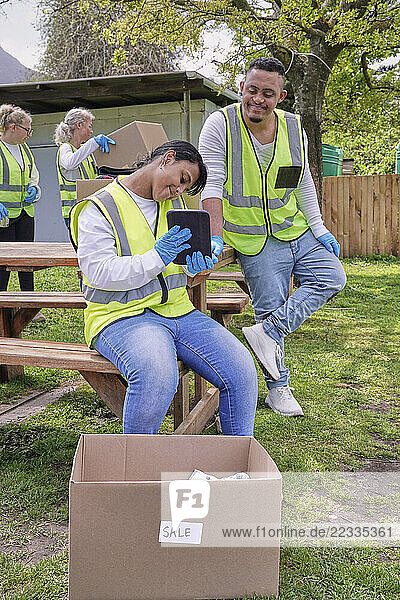 Female volunteer checking tablet during packaging donation boxes