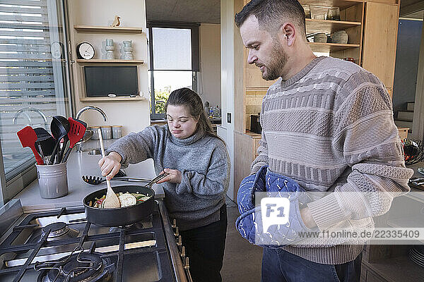 Man and woman with Down Syndrome preparing dinner in kitchen