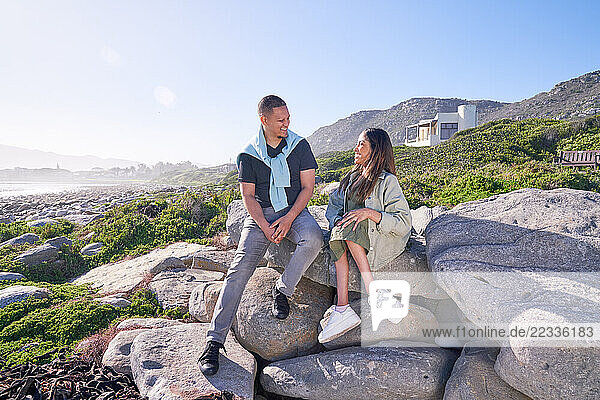 Man and disabled woman sitting in coastal landscape