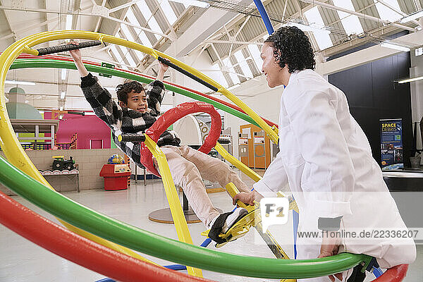 Instructor assisting boy on gyroscope at science center