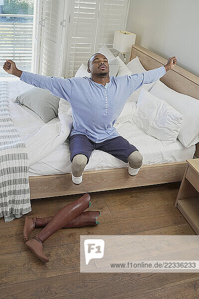 Man with amputated legs sitting on bed