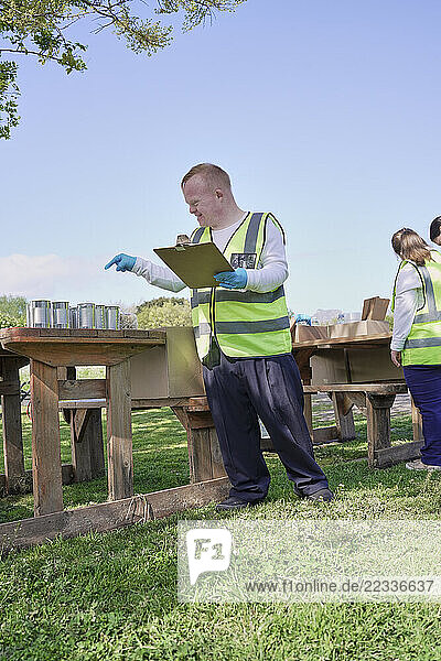 Two volunteers packaging donation boxes at table outdoors