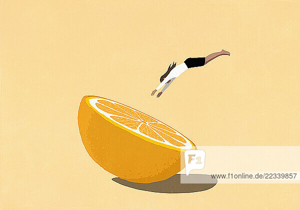Woman diving into large cross section of orange on yellow background