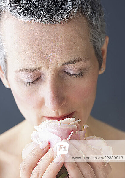 Close up of Mature Woman Smelling Rose