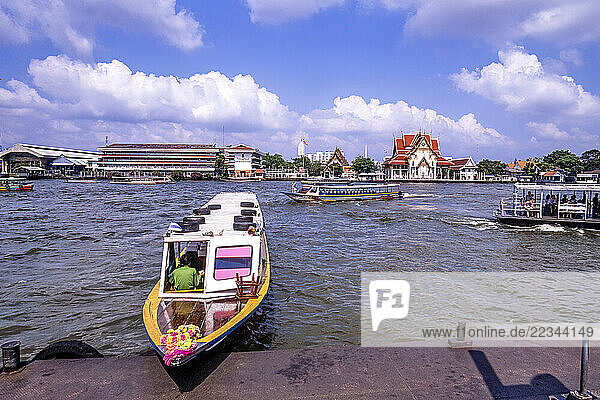 Chao Phraya River and boat traveling along the shoreline in Bangkok  Thailand; Bangkok  Thailand