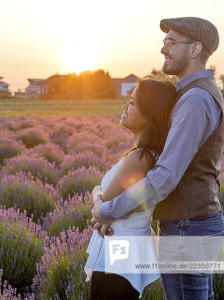 Young couple sharing a romantic moment in a lavender field at sunset; Woodenville  Washington  United States of America