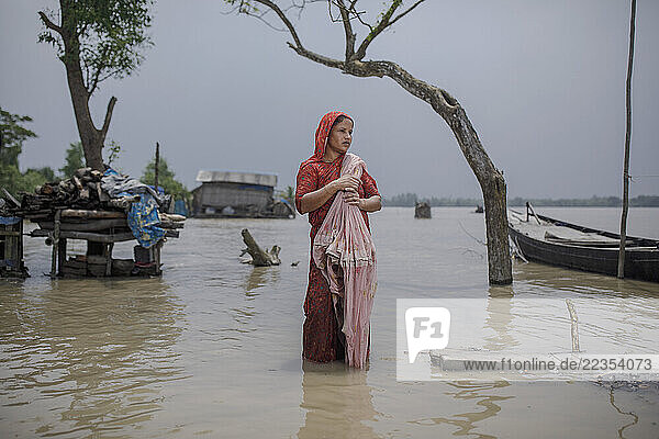 Woman in front of her house flooded by the sea level high tide water at the coastal village Kalabigi in Khulna  Bangladesh on 31 August 2023; Khulna  Dhaka  Bangladesh