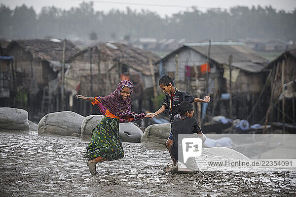 Children playing in the rain at the Kalabogi village in Khulna  Bangladesh  on 03 September 2023. In the coastal areas of Southern Bangladesh like Kalabogi  people‘s livelihoods depend entirely on nature. Climate change has severe impacts on the natural environment. The consequences range from rising sea levels leading to salinization of soils and groundwater to erratic rainfall patterns and more frequent and destructive tropical cyclones. People living in coastal areas fight for their survival every day; Khulna  Dhaka  Bangladesh