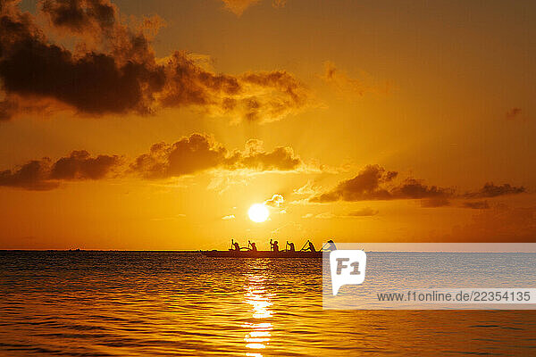 Outrigger canoe paddlers at sunset on Tumon Bay off Guam  Micronesia; Asan  Guam  Micronesia