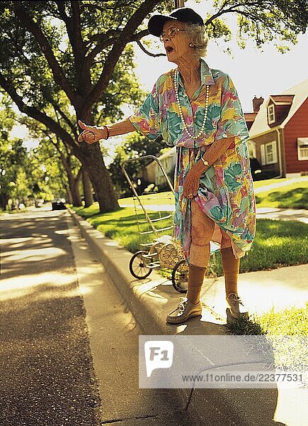 Older woman hitching a ride from the sidewalk in a neighborhood setting.