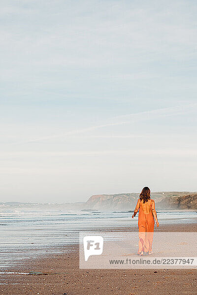 Woman walking alone on the beach along the shoreline