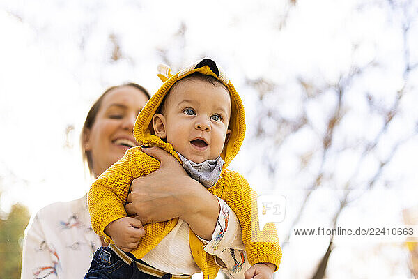 Happy mother carrying baby boy in a park