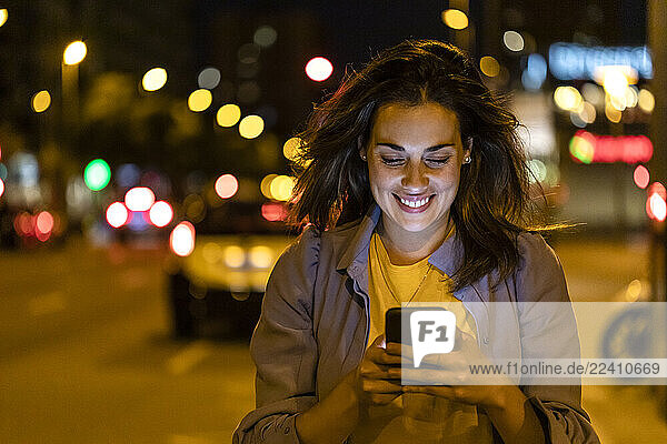 Young woman using smartphone in the city at night