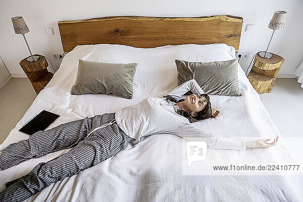 Relaxed woman lying on bed at home