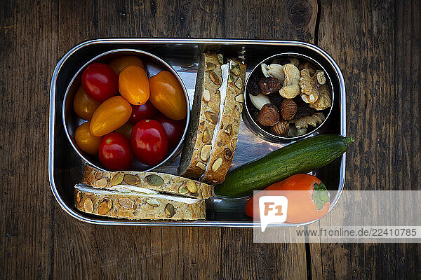 Lunchbox with pumpkin seed bread  cucumber  bell pepper  tomatoes and nuts
