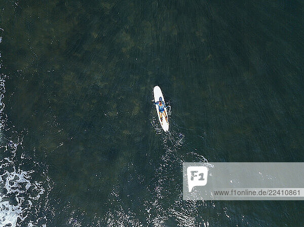 Aerial view of female surfer lying on surf board