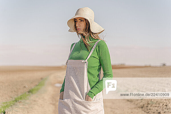 Young woman standing on dry field  with hands in pockets