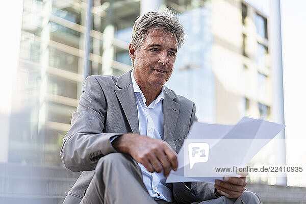 Mature businessman reviewing documents in the city