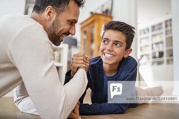 Father and son lying on the floor at home arm wrestling