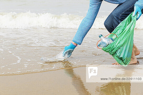 Woman collecting ocean waste during a beach cleanup at the North Sea