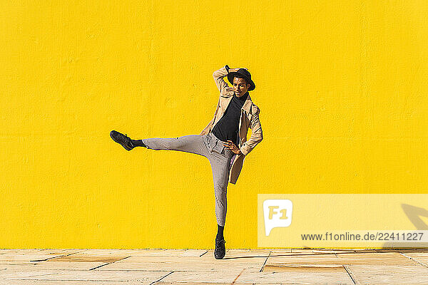 Young man dancing in front of yellow wall