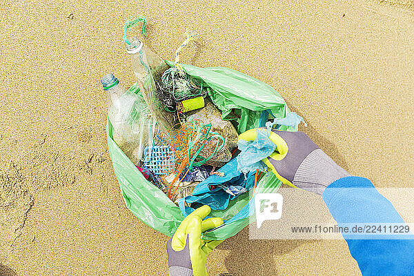 Hands collecting plastic waste on a North Sea beach for environmental protection