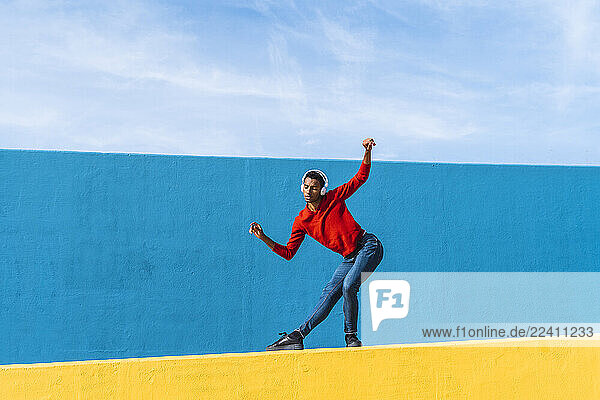 Young man with headphones  listening music  dancing on yellow wall