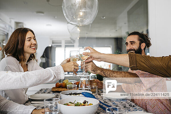 Happy friends having lunch together clinking glasses