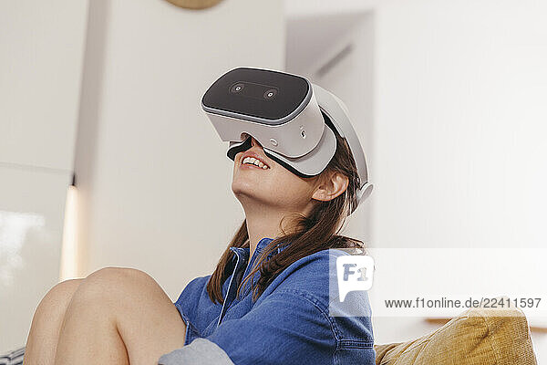 Young woman using VR glasses at home