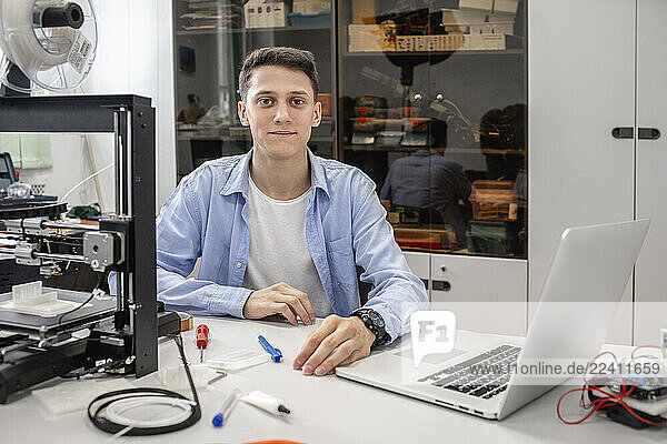 Student setting up 3D printer  using laptop
