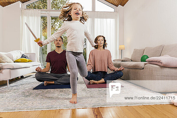 Exuberant girl with parents meditating at home