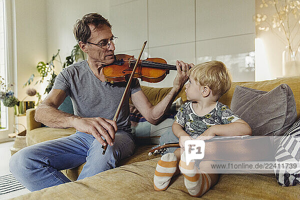 Toddler watching his father playing violin