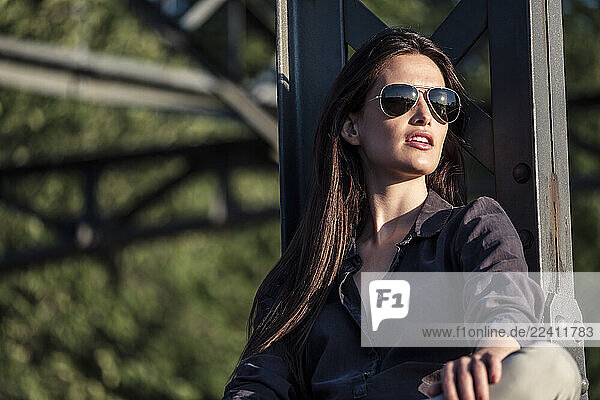Young woman enjoying the evening sun  sitting on a bridge