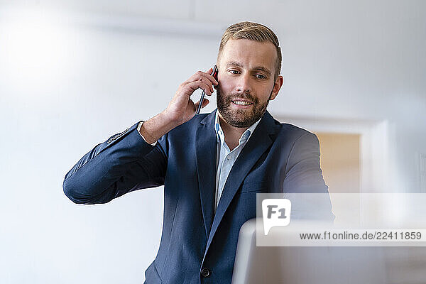 Smiling businessman on cell phone in office