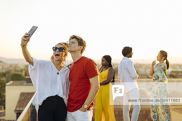 Young woman and man taking a selfie during a party in the evening