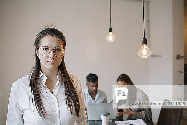 Portrait of young womann in office with colleagues in background