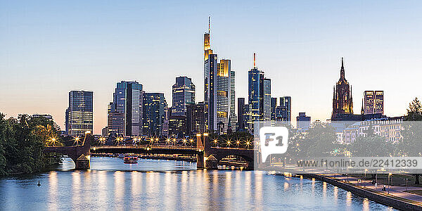 Illuminated buildings by river against clear sky during sunset in Frankfurt  Germany