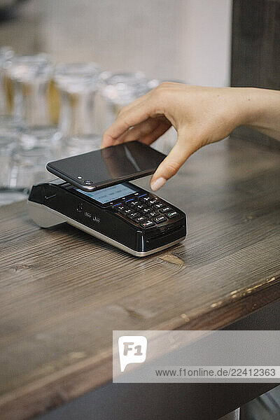 Customer paying cashless with smartphone in a cafe
