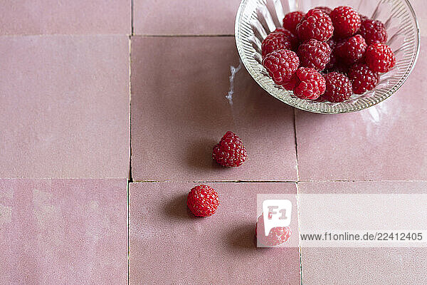 Raspberries in a bowl on a tiled surface in a studio setting