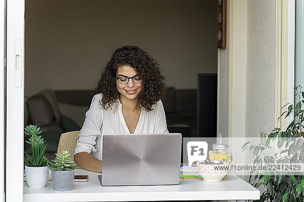 Smiling young woman using laptop at desk