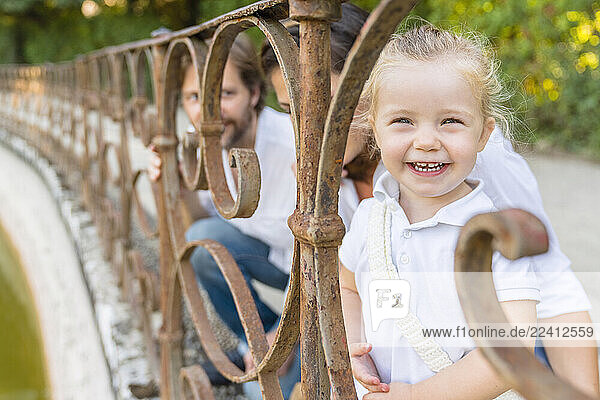 Portrait of happy little girl with parents at a pond
