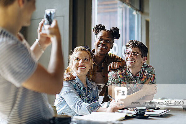 Students sitting in cafe  taking samrtphone selfies