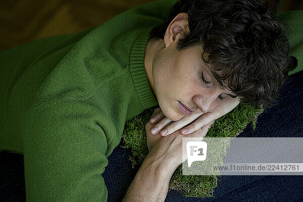 A young man in a green sweater is resting at home  enjoying a peaceful afternoon nap.