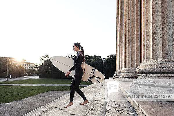 Young woman with surfboard on the way to Eisbach  Munich  Germany