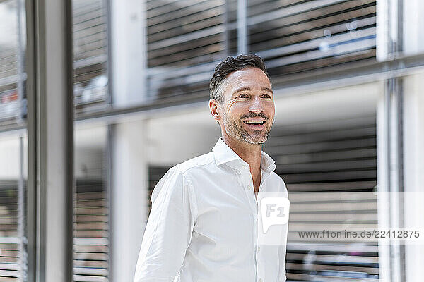 Portrait of a self-confident man in a white shirt smiling indoors at the office