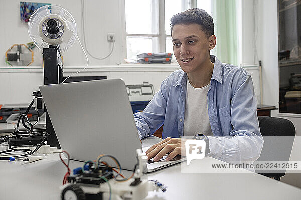 Student setting up 3D printer  using laptop