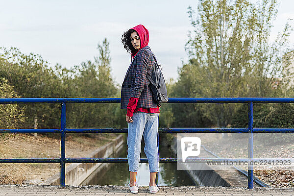 Portrait of young woman with backpack standing on a bridge