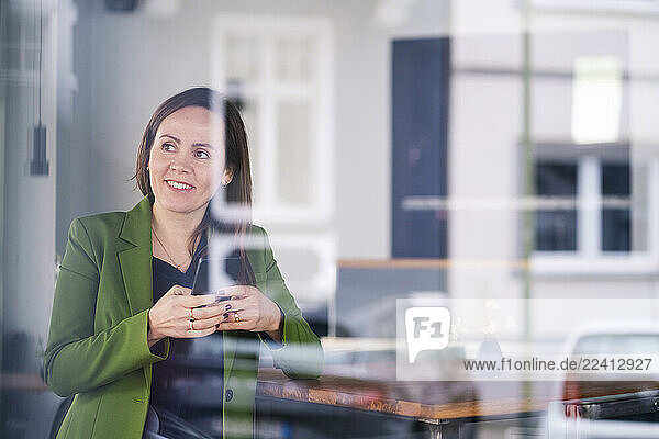 Woman in green jacket using smartphone at café