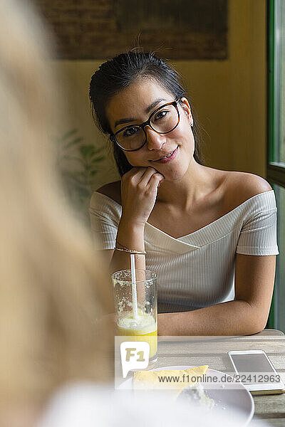 Portrait of smiling young woman sitting at table with a smoothie