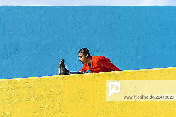 Young dancer stretching on yellow wall